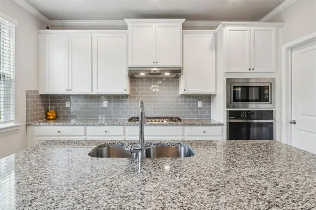 a kitchen with stainless steel appliances granite countertop a stove a sink and a white cabinets