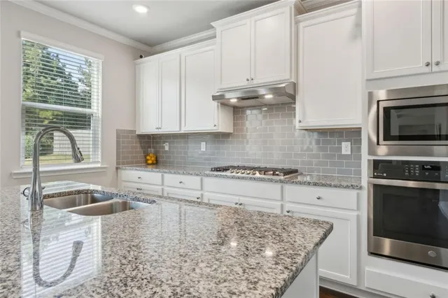 a kitchen with granite countertop a sink a stove and cabinets