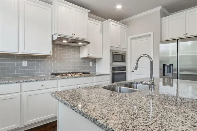 a kitchen with granite countertop a stove a sink and a microwave