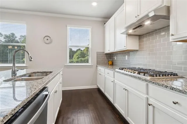 a kitchen with a stove a sink a window and cabinets