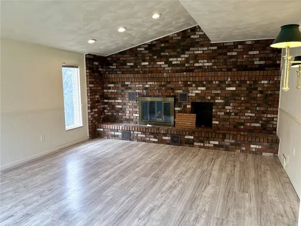 a view of empty room with wooden floor and fireplace