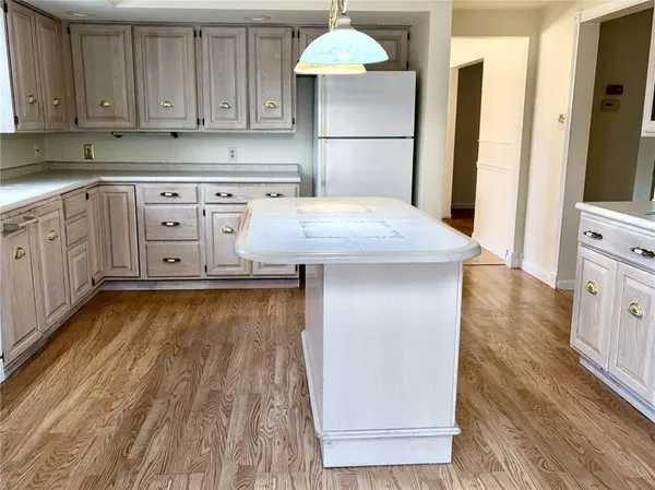 a kitchen with granite countertop a refrigerator a stove and white cabinets with wooden floor