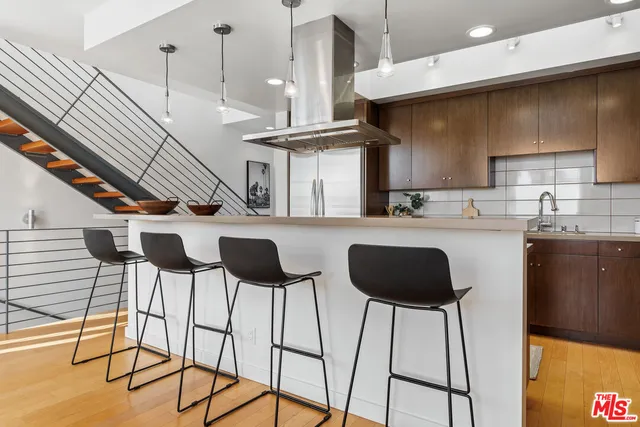 a kitchen with stainless steel appliances kitchen island granite countertop a table chairs and a wooden cabinets