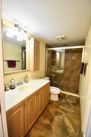 a bathroom with a granite countertop sink toilet a mirror and shower