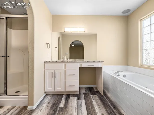 a bathroom with a tub sink vanity and a mirror