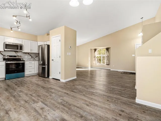 a open kitchen with stainless steel appliances a refrigerator and a stove top oven