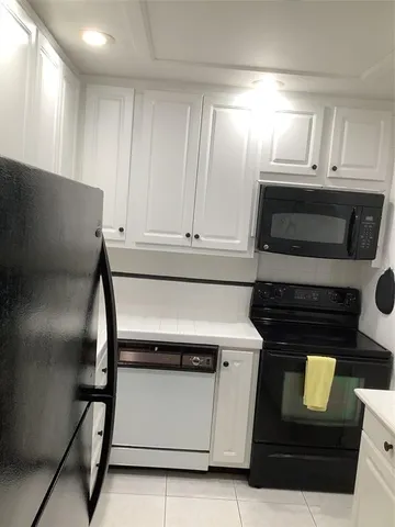 a kitchen with granite countertop white cabinets and black appliances