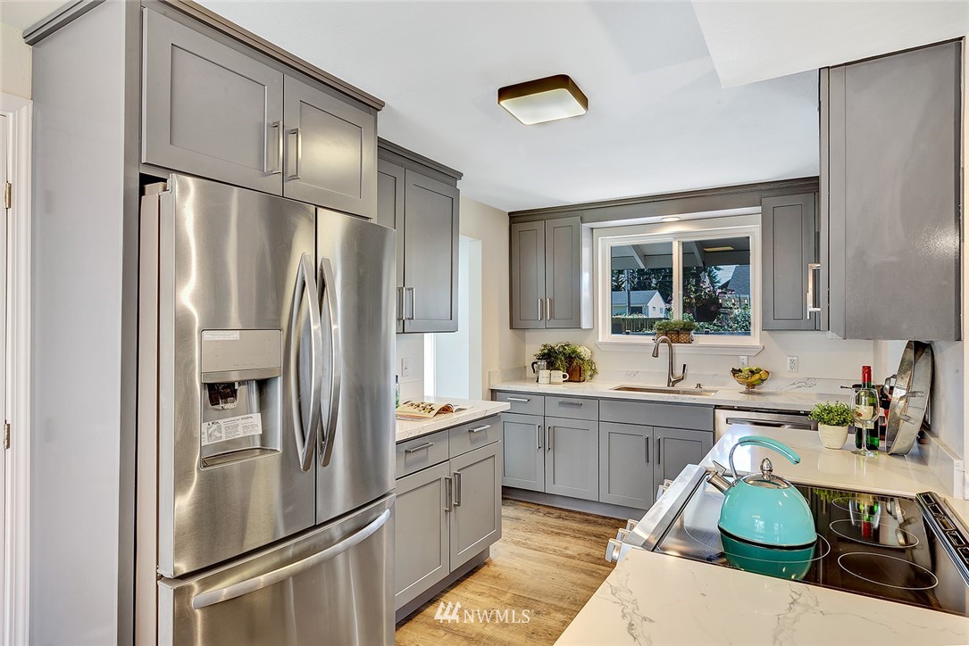 2212 Edmonds Avenue Northeast Renton, WA 98056 - Photo 8 of 18 a kitchen with stainless steel appliances granite countertop a refrigerator a sink dishwasher a stove with white cabinets and wooden floor
