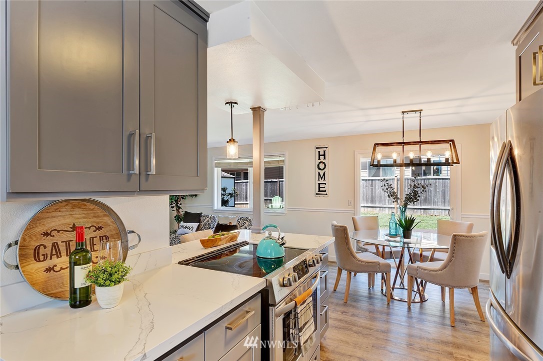 2212 Edmonds Avenue Northeast Renton, WA 98056 - Photo 10 of 18 a kitchen with stainless steel appliances a dining table chairs and a white refrigerator