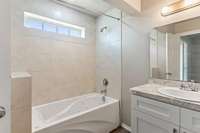 a bathroom with a tub a sink and mirror