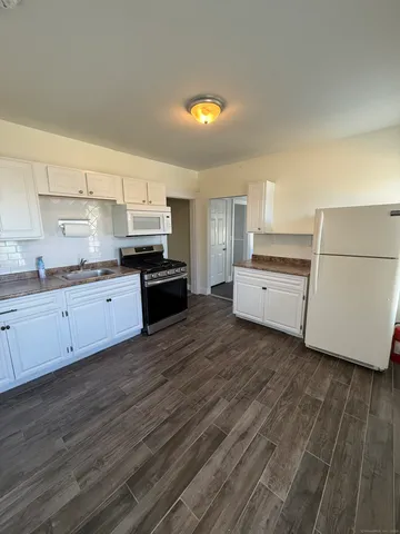a kitchen with wooden floors and white appliances