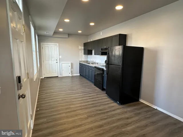 a kitchen with stainless steel appliances granite countertop a refrigerator and a wooden floor