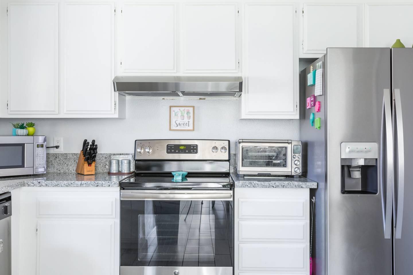 82191 Waring Way Indio, CA 92201 - Photo 12 of 42 a kitchen with stainless steel appliances a refrigerator a stove and white cabinets