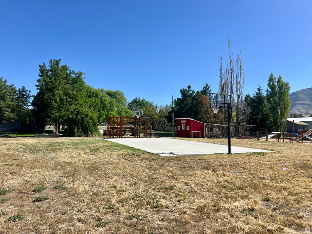 812 East Bates Cyn Road Tooele, UT 84074 - Photo 121 of 144 Expansive outdoor space featuring a concrete sports court with two basketball hoops, a red storage shed, mature trees, and a wooden play structure
