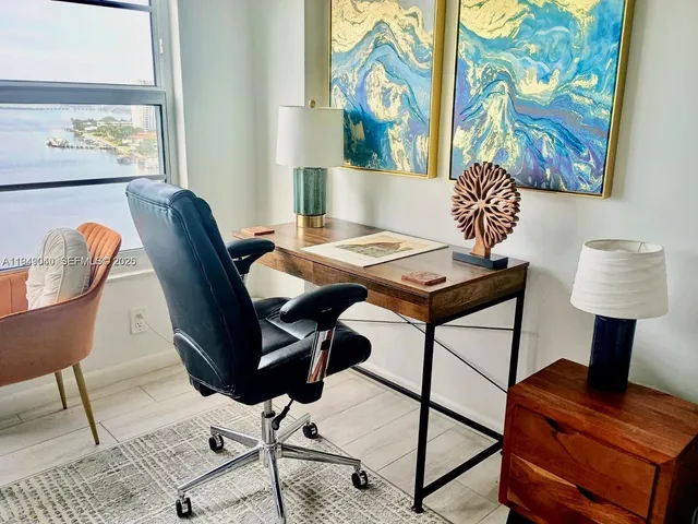a view of a workspace with furniture and a window
