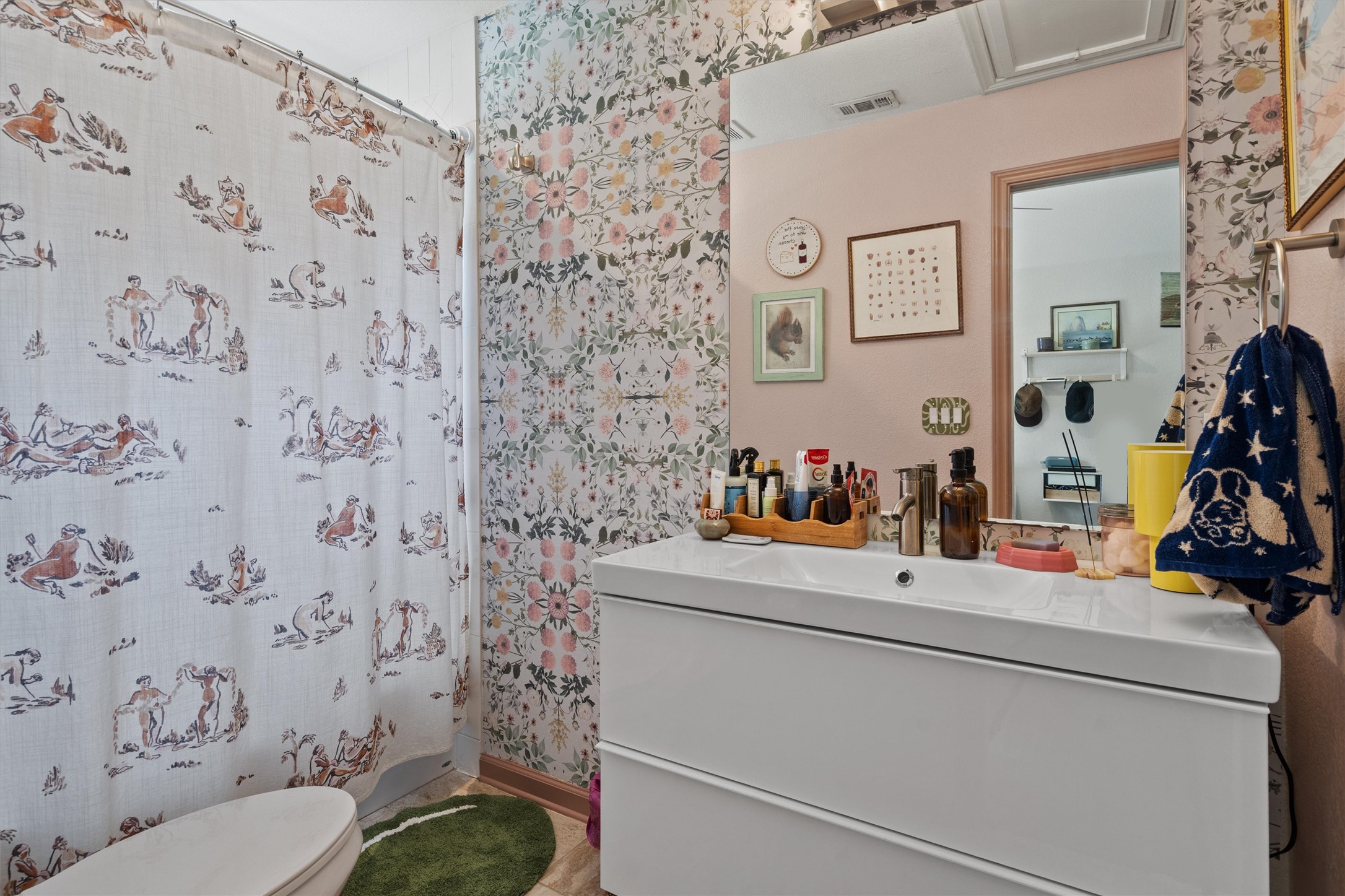 1147 Webberville Road Austin, TX 78721 - Photo 17 of 37 A well-appointed bathroom features a modern vanity and a playfully patterned shower curtain, creating a cheerful, functional space.