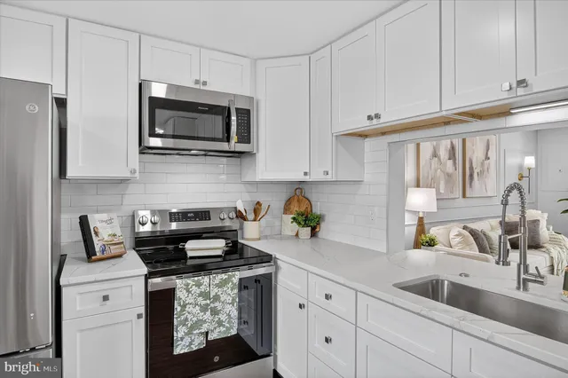 a kitchen with stainless steel appliances granite countertop white cabinets a stove a sink and dishwasher