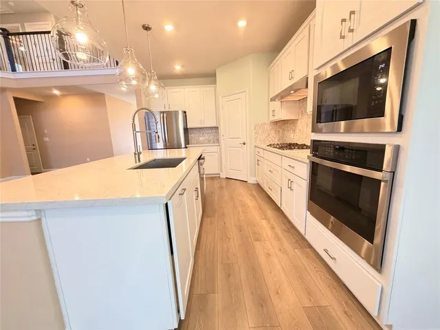 a large kitchen with stainless steel appliances a refrigerator and a stove top oven