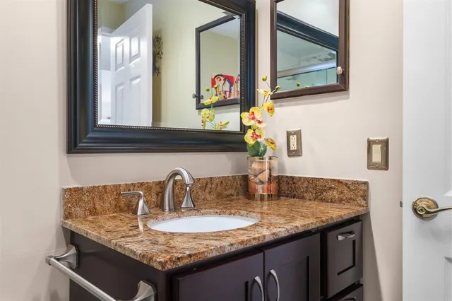 a bathroom with a granite countertop sink and a mirror