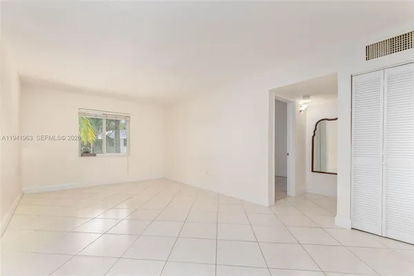 an empty room with a white cabinet and mirror