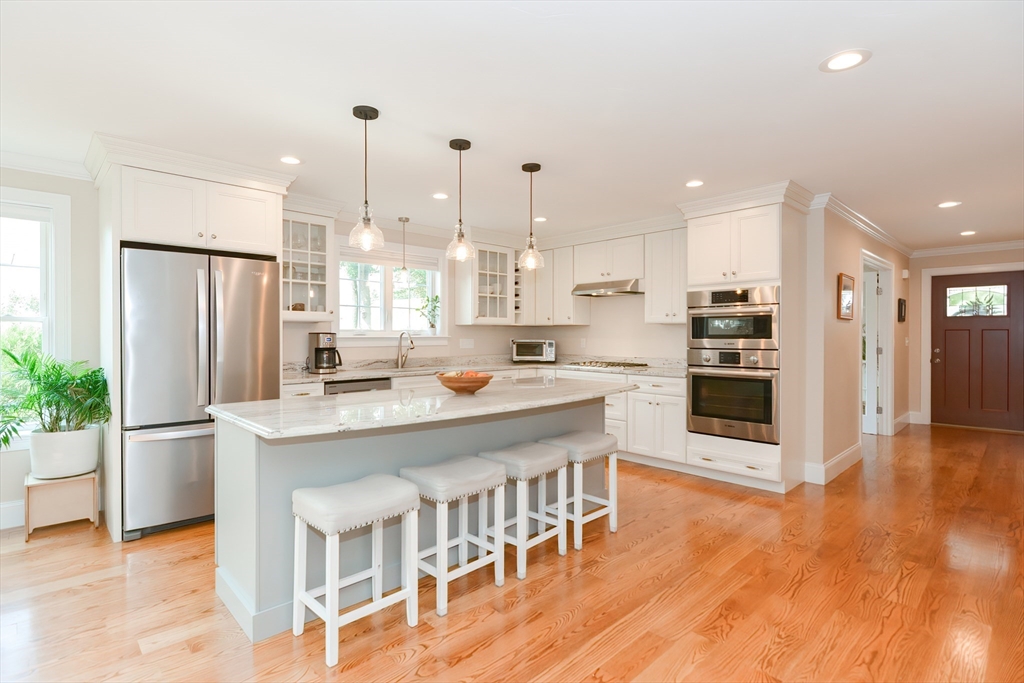 29 Webb Place, Unit A Mansfield, MA 02048 - Photo 3 of 42 a kitchen with stainless steel appliances kitchen island granite countertop a refrigerator a stove a sink and a dining table with wooden floor