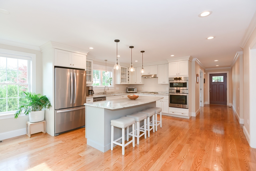 29 Webb Place, Unit A Mansfield, MA 02048 - Photo 9 of 42 a kitchen with stainless steel appliances kitchen island granite countertop a refrigerator a stove a sink and a wooden floors
