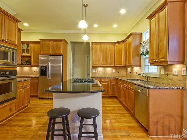 1812 Stannard Trail Raleigh, NC 27612 - Photo 6 of 25 Features of the spacious kitchen include stainless appliances, tile backsplash with decorative tile accents, under cabinet lighting, brushed nickel hardware, and recessed lighting. Kitchen