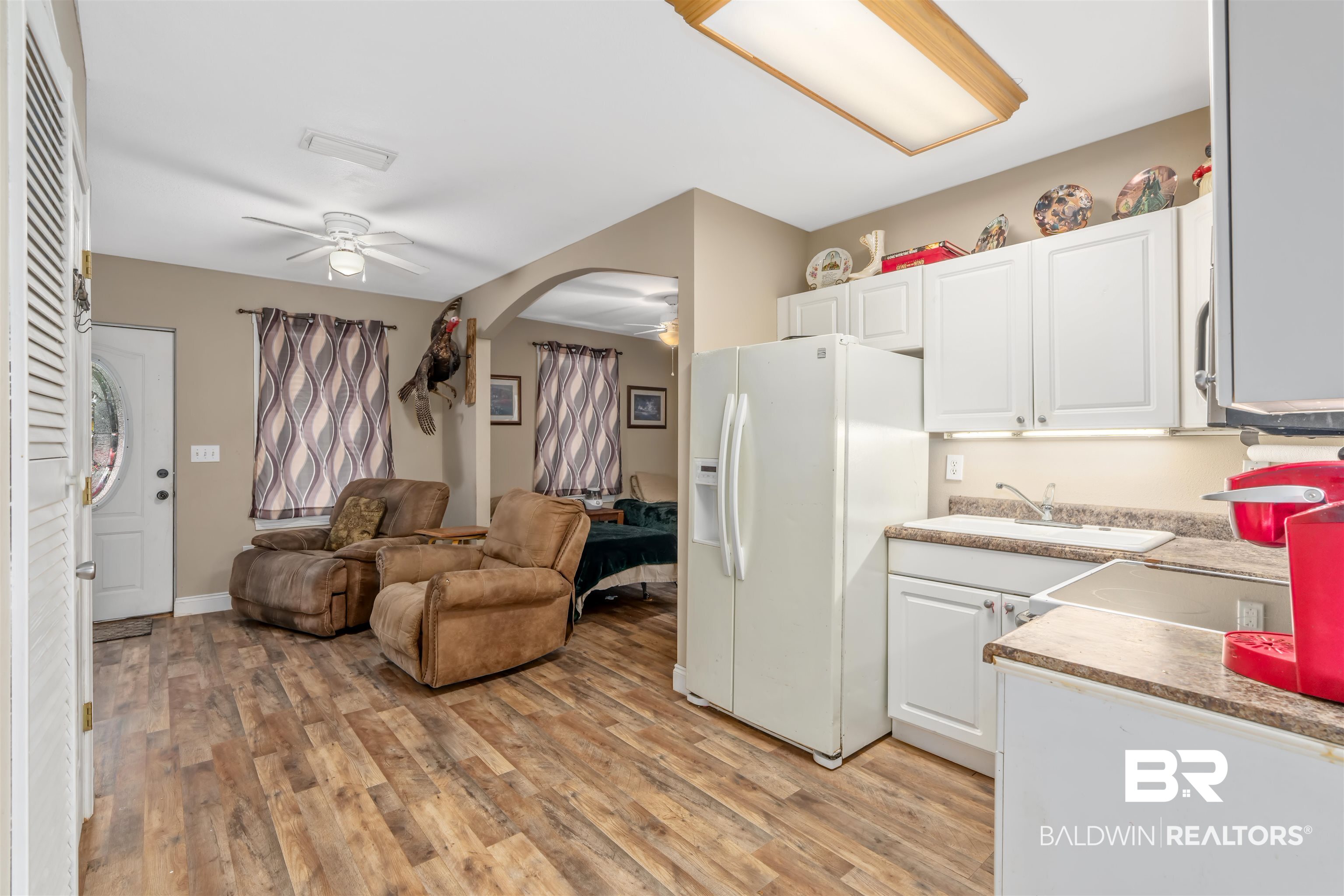 23186 Pecan Street Robertsdale, AL 36567 - Photo 36 of 36 Kitchen featuring ceiling fan, white fridge with ice dispenser, light wood-type flooring, white cabinetry, and open floor plan