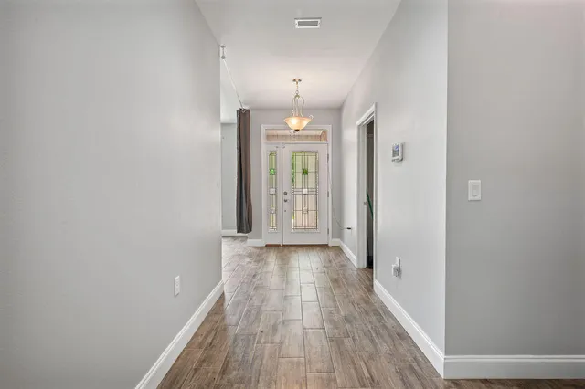a view of a hallway with wooden floor and a chandelier