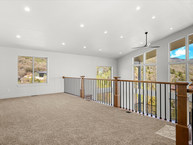 1159 North Broad Hollow Road Garden City, UT 84028 - Photo 41 of 55 Expansive loft space with neutral carpeting, recessed ceiling lighting, a contemporary ceiling fan, a wood-finish and wrought iron railing, and large windows with mountain scenery