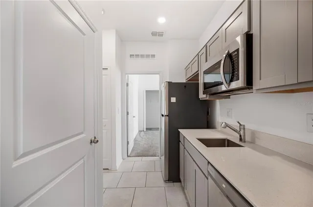 a kitchen with stainless steel appliances a sink dishwasher a microwave a stove and white cabinets