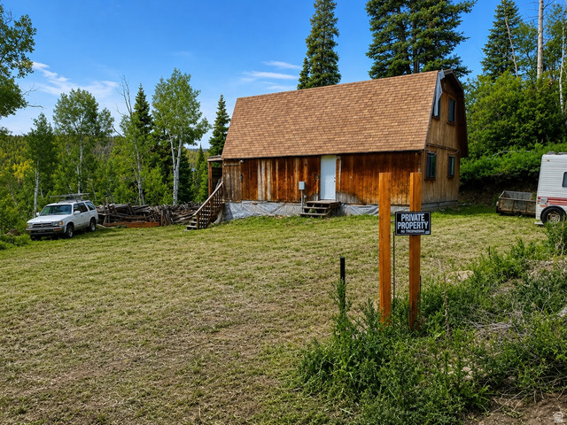 1005 Oak Road Coalville, UT 84017 - Photo 1 of 1 Wood-sided structure featuring a gambrel roof and multiple windows, surrounded by a natural landscape of mature trees and a grassy area