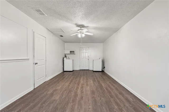 an empty room with a windows and a ceiling fan