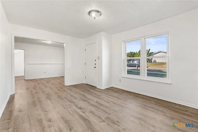 an empty room with wooden floor and windows