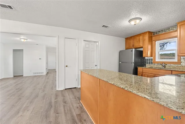 a kitchen with stainless steel appliances granite countertop a refrigerator a stove and a sink with large window