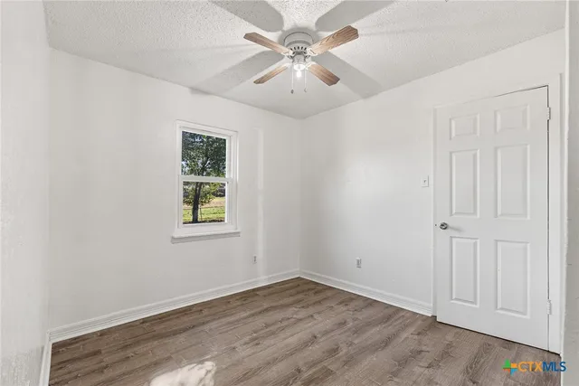 an empty room with a window and a ceiling fan