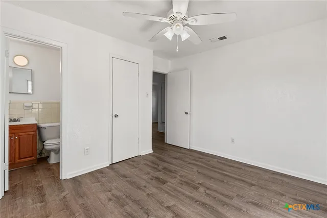 an empty room with wooden floor and ceiling fan
