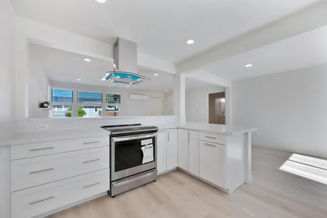 a kitchen with stainless steel appliances a stove and white cabinets with wooden floor