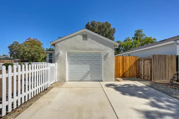 a view of a house with a small yard and large trees