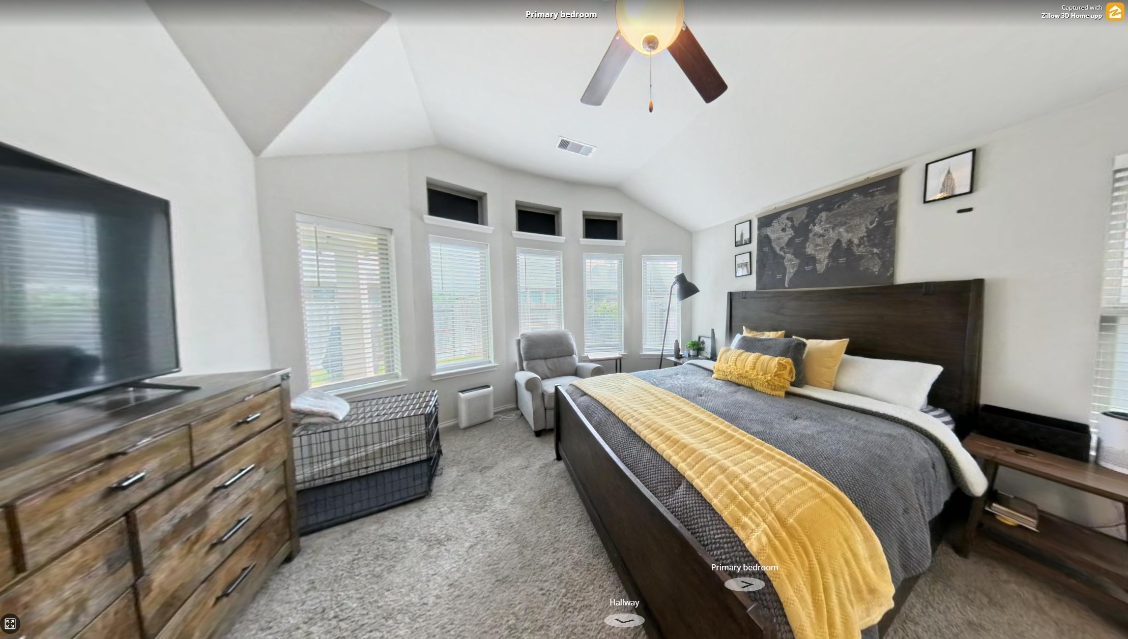 718 Santa Elena Trail Conroe, TX 77304 - Photo 13 of 29 Discover the serene charm of this spacious primary bedroom, featuring abundant natural light from its large windows, complemented by a stylish ceiling fan, cozy carpeted floor, and elegant furnishings, perfect for relaxation and comfort.