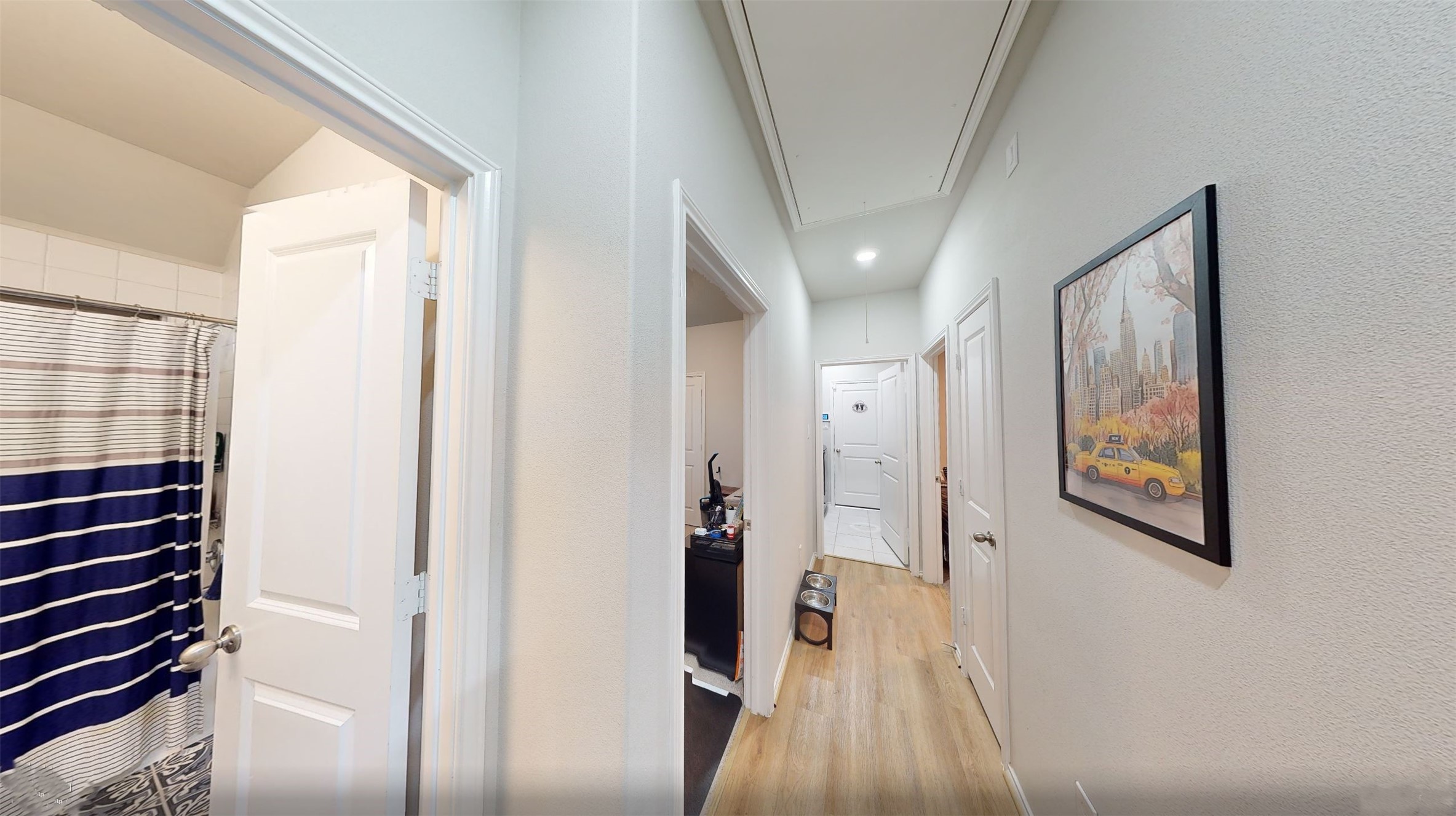 718 Santa Elena Trail Conroe, TX 77304 - Photo 15 of 29 This inviting hallway, accessed from the kitchen, features warm wood floors, artful decor, and leads to multiple rooms, creating a welcoming pathway through your home.