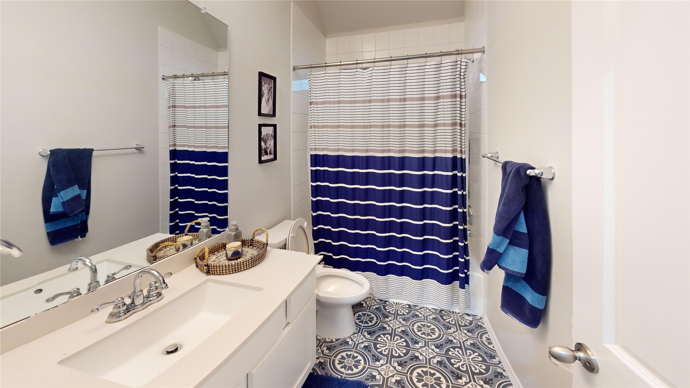 718 Santa Elena Trail Conroe, TX 77304 - Photo 17 of 29 This inviting full bath boasts a modern design with stylish patterned flooring, a chic striped shower curtain, and a pristine vanity, perfect for a refreshing daily retreat.