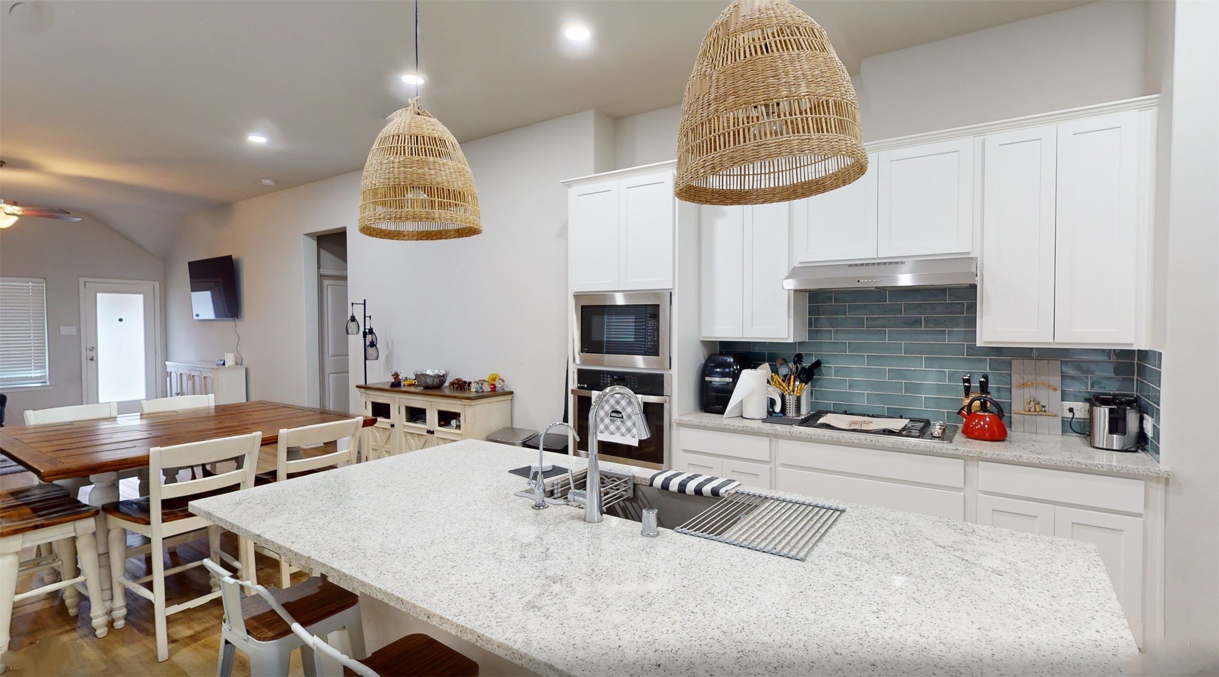 718 Santa Elena Trail Conroe, TX 77304 - Photo 3 of 29 This inviting kitchen blends modern elegance with cozy charm, featuring sleek white cabinetry, a stunning marble island, and warm wicker pendant lighting, perfect for both entertaining and everyday family meals.