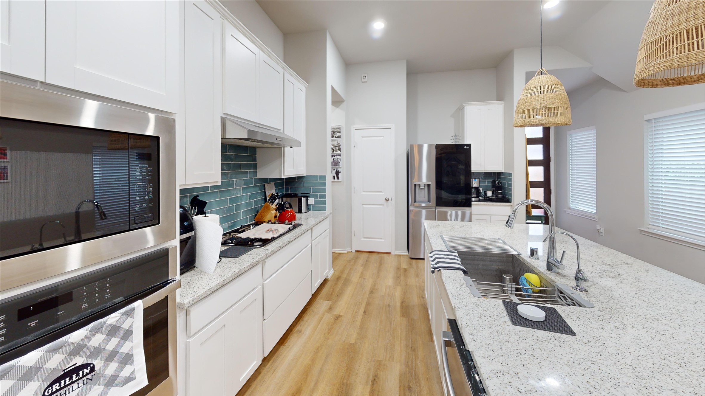 718 Santa Elena Trail Conroe, TX 77304 - Photo 5 of 29 This modern kitchen boasts sleek stainless steel appliances, elegant white cabinetry, a spacious island with a stylish sink, and warm wooden floors, creating the perfect blend of functionality and charm.
