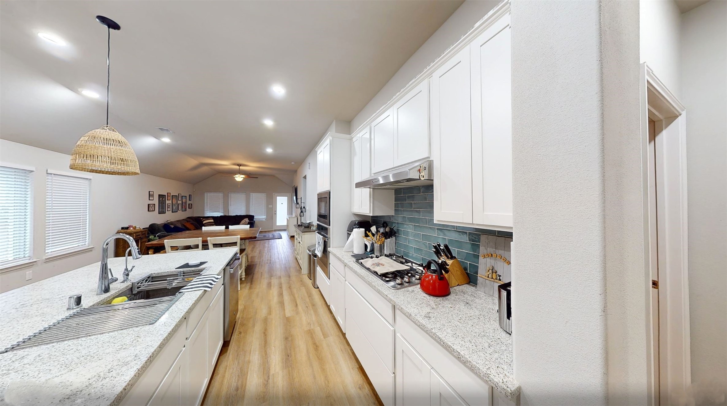 718 Santa Elena Trail Conroe, TX 77304 - Photo 6 of 29 This inviting kitchen boasts sleek white cabinetry, elegant granite countertops, and a stylish tile backsplash, seamlessly flowing into a spacious open-concept living area, perfect for modern living and entertaining.