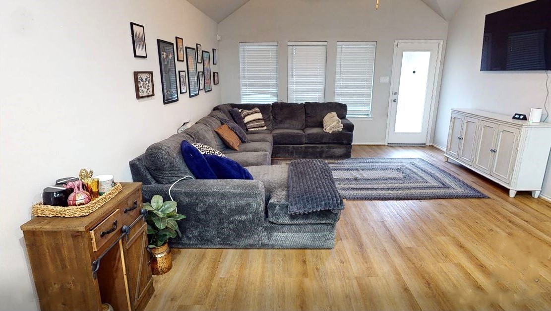 718 Santa Elena Trail Conroe, TX 77304 - Photo 9 of 29 This inviting living room features a cozy sectional sofa, warm wooden floors, and abundant natural light, creating a perfect blend of comfort and style for relaxation and entertaining.