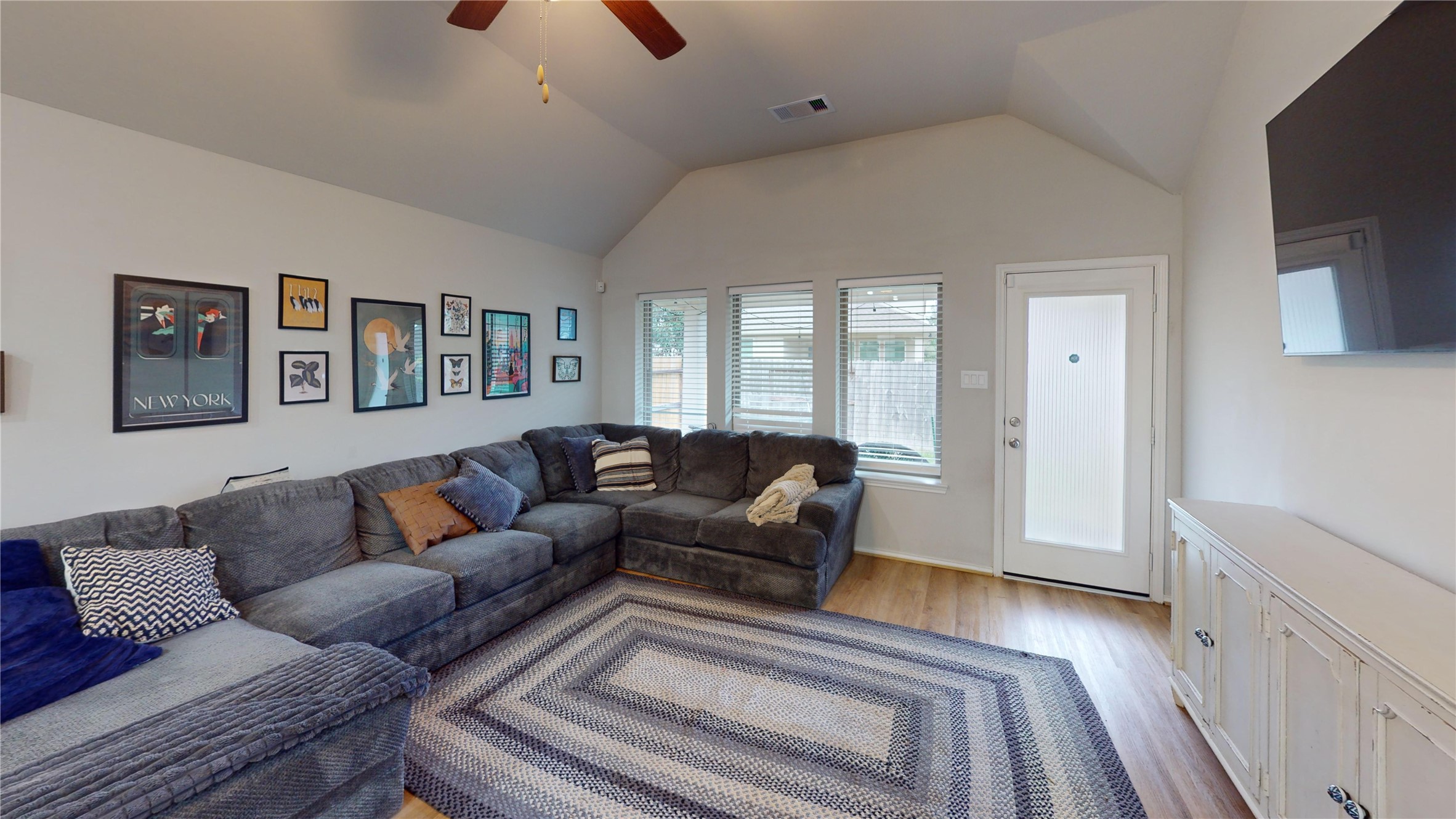718 Santa Elena Trail Conroe, TX 77304 - Photo 10 of 29 Step into this inviting living room, where natural light floods through large windows onto a cozy sectional, complemented by stylish decor and a sleek entertainment setup.