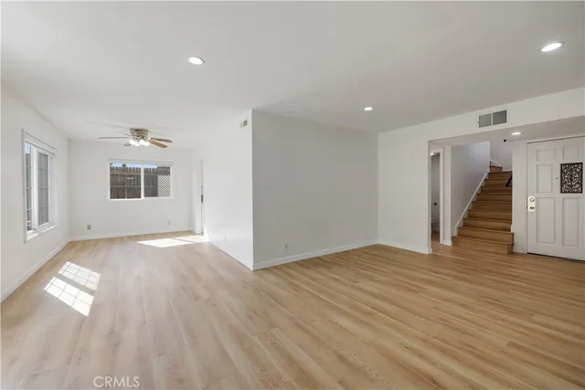 a view of an empty room with wooden floor and stairs