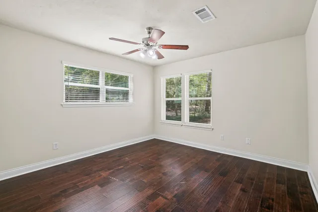 a view of an empty room with wooden floor and a window