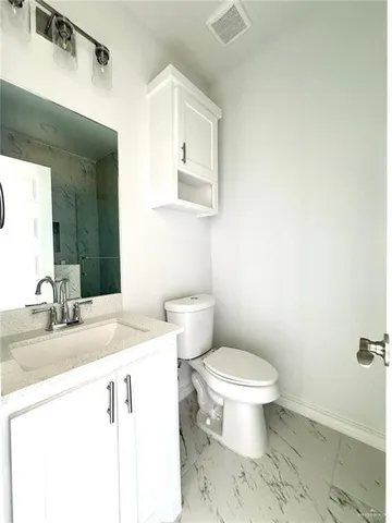 a bathroom with a granite countertop toilet sink and mirror